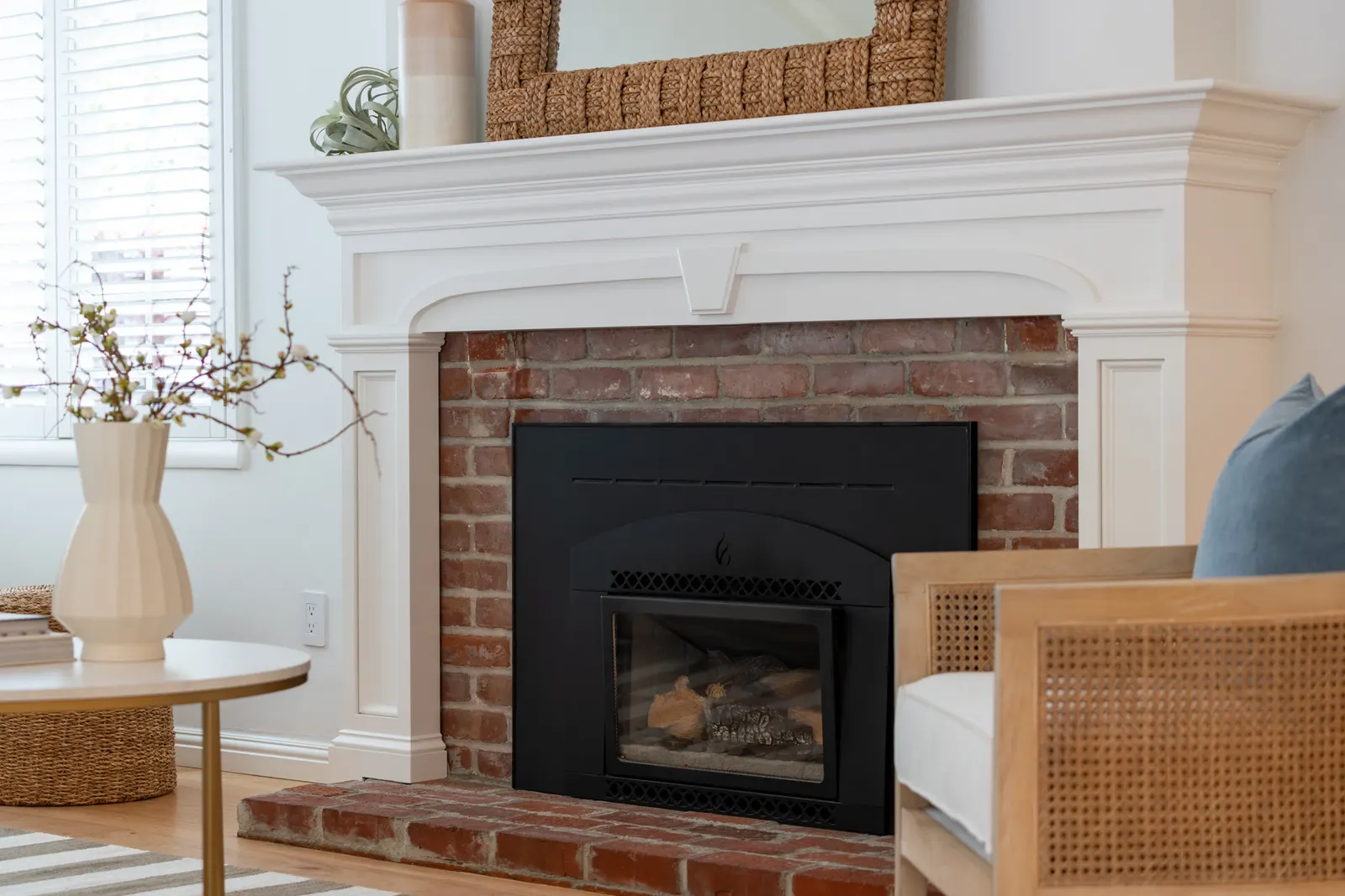 Brick fireplace with a black inset firebox and white mantel in a bright living room